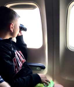 Life that Counts - Boy looking out of a plane with binoculars.